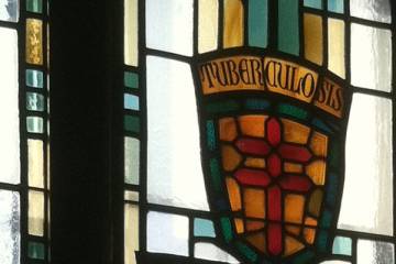 Stained glass window with double cross and the word Tuberculosis