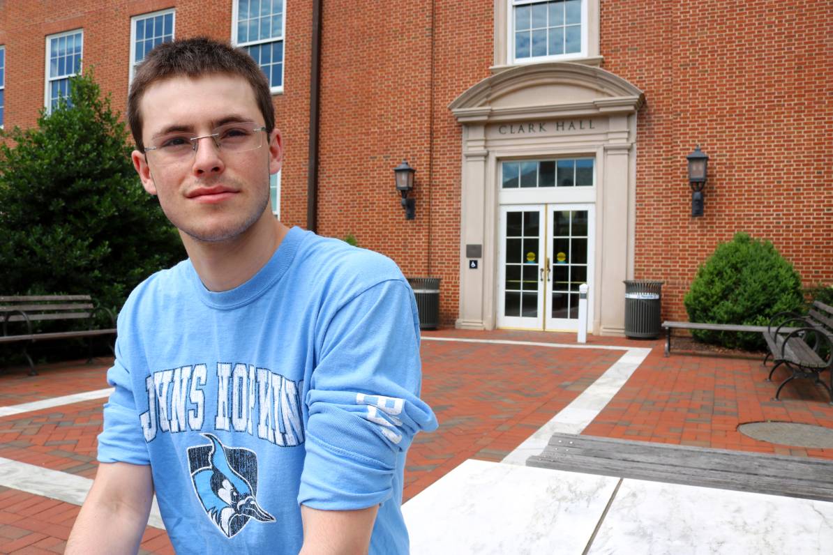 Arik poses for a photo in a blue, long-sleeve Johns Hopkins shirt