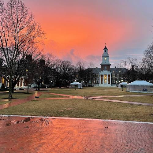 Orange sunset over a campus quad and academic buildings