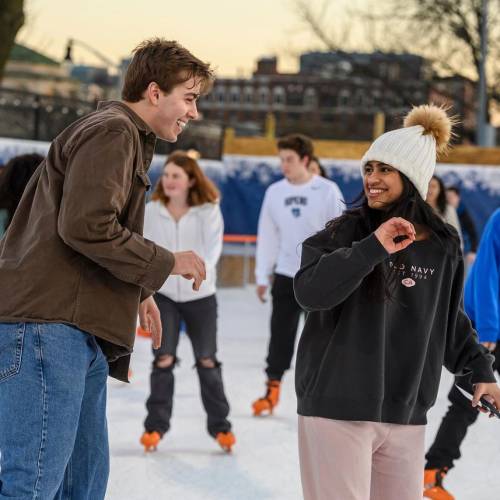Two people smile at each other while ice skating