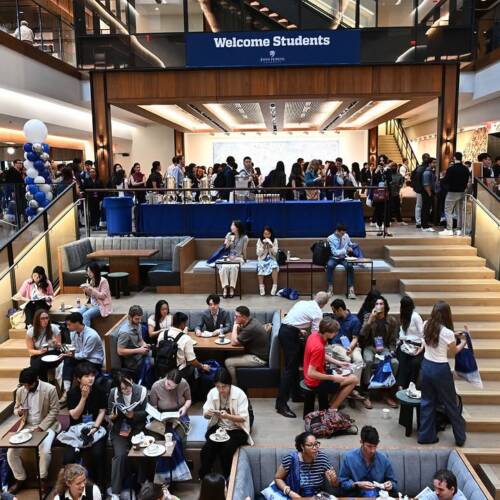 Dozens of people fill the modern, tiered interior of a building